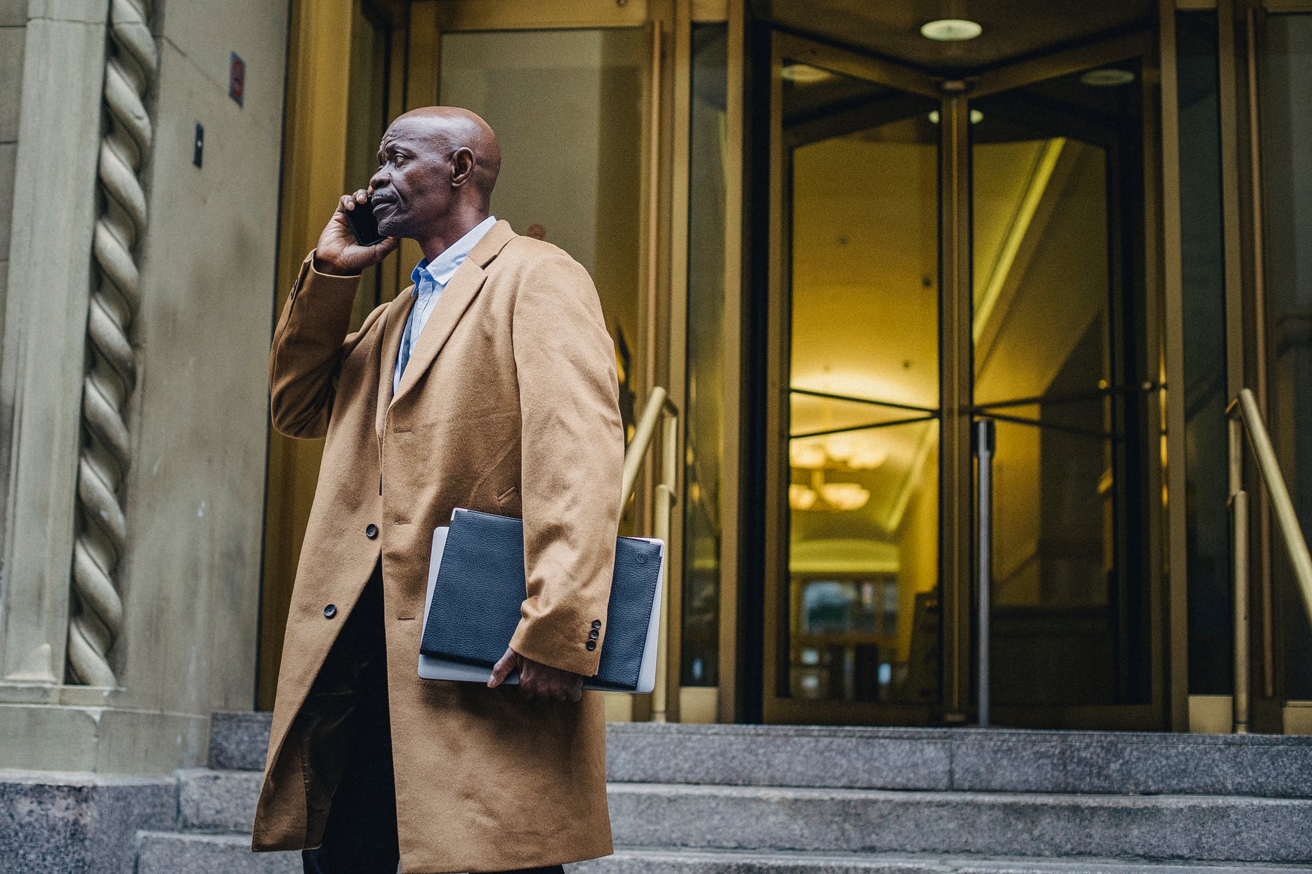 black businessman speaking on smartphone near building