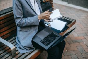 crop black businesswoman writing information in planner while working outside